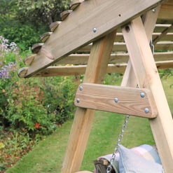 Natural wooden outdoor swing set in a lush garden with blooming flowers and greenery, perfect for backyard relaxation and family fun.