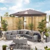 Stylish outdoor patio with sectional sofa, large umbrella, modern decor, and lush potted plants providing a cozy and inviting backyard relaxation space.