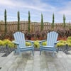 Bright outdoor garden seating with two blue Adirondack chairs on a paved patio, lush landscaping, and a wooden privacy fence, perfect for relaxing in a beautifully designed backyard garden.