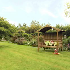Elegant garden seating area with a wooden gazebo, lush greenery, and vibrant flowering plants, perfect for outdoor relaxation and enhancing garden aesthetics.