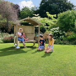 Kids playing in a lush, green backyard garden with a wooden summerhouse, surrounded by vibrant flowering bushes and trees, creating a perfect outdoor family space.