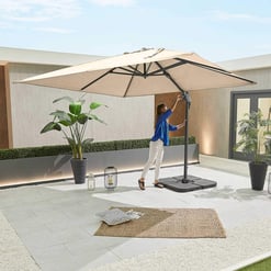 Enjoying a spacious patio with modern outdoor furniture, a large beige umbrella, and lush potted plants for a perfect backyard relaxation area.