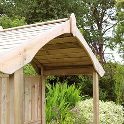 A wooden garden arbor and fencing surrounded by lush greenery and colorful plants in a backyard landscape.