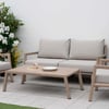 Elegant outdoor patio furniture set with beige cushions, surrounded by lush decorative plants, perfect for garden relaxation and outdoor entertaining.