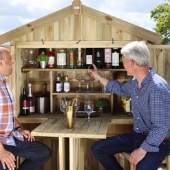 Enjoying outdoor wine tasting in a custom wooden backyard bar with ample storage, perfect for entertaining friends and family in a beautiful garden setting.