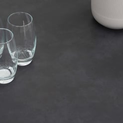 Crystal-clear drinking glasses arranged on a sleek dark surface, with a modern white vase partially visible in the background, showcasing stylish home decor and tabletop essentials.