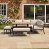 Stylish outdoor patio furniture with comfortable cushions on a garden patio, perfect for relaxing and entertaining near a brick house with lush flowering plants.