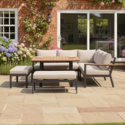 Stylish outdoor patio furniture with comfortable cushions on a garden patio, perfect for relaxing and entertaining near a brick house with lush flowering plants.