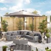 Modern outdoor patio with grey sectional sofa, black and white patterned cushions, large umbrella, potted plants, and ambient lighting, showcasing stylish garden furniture and landscaping.
