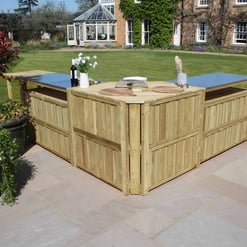 Natural wood outdoor grilling station with stainless steel countertops and a garden setting for backyard cooking and entertaining.