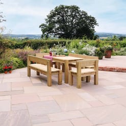 Natural wooden outdoor dining table set on a spacious garden patio, surrounded by lush plants and scenic countryside views, ideal for garden furniture and outdoor entertaining.