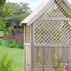Natural wood garden shed with lattice detail in lush backyard, perfect for outdoor storage and garden organization.
