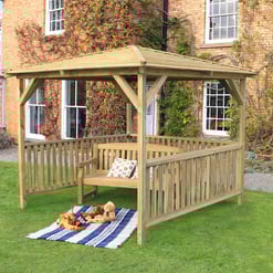 A wooden garden gazebo with seating and a roof, perfect for outdoor relaxation and gatherings, installed on a lush green lawn in front of a brick house with ivy-covered walls.