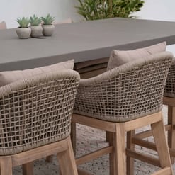 Stylish outdoor dining table with woven rattan armchairs, perfect for garden or patio decor, showcasing durable furniture and comfortable seating options for outdoor entertaining.