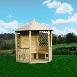 Wooden garden gazebo with lattice sides and a shingled roof on lush green lawn, perfect for outdoor relaxation and entertaining.