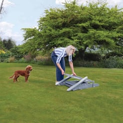 Light gray garden lawn aerator in use on lush green backyard lawn, woman with dog enjoying outdoor gardening and yard maintenance, perfect for home and garden improvement projects at Empire Home and Garden.