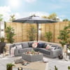 Outdoor patio with modern sectional sofa, large umbrella, decorative pillows, and lush greenery, perfect for relaxing and entertaining in a stylish home garden setting.