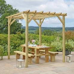 Solid wood outdoor pergola with string lights over a dining table, perfect for garden or patio entertaining in a picturesque landscape setting.