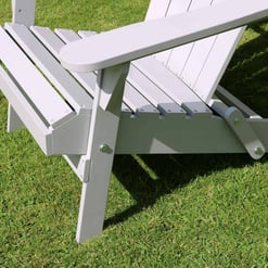 Stainless steel outdoor garden bench with slatted seat and armrests in a well-maintained lawn setting.