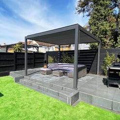 Stylish outdoor patio with a modern pergola, comfortable seating, and elegant stone flooring perfect for relaxing or entertaining in a landscaped backyard.
