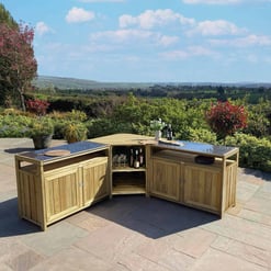 Outdoor wooden bar cart with glassware and wine bottles on a patio overlooking a lush garden and rolling hills, perfect for outdoor entertaining and garden decor.