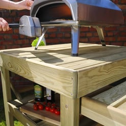 Portable outdoor pizza oven on a wooden garden table, perfect for backyard outdoor cooking and entertaining.