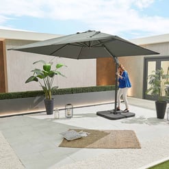 Relaxing outdoor patio with large adjustable umbrella, potted plants, cozy rug, and decorative lanterns, perfect for backyard entertaining and outdoor living.