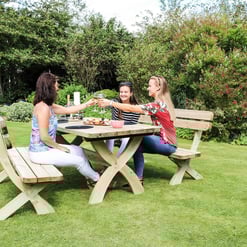 Relaxed outdoor garden dining with friends on a rustic wooden picnic table surrounded by lush greenery, perfect for outdoor entertaining and summer gatherings.