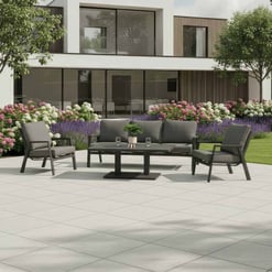 Modern outdoor patio furniture set on a spacious tile patio with lush garden and contemporary architecture, perfect for relaxing in a stylish garden or backyard space.