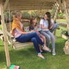 Relaxing outdoor garden swing with family enjoying a beautiful day in the yard. Perfect for outdoor fun, family time, and garden relaxation with kids and pets.