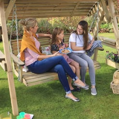 Relaxing outdoor garden swing with family enjoying a beautiful day in the yard. Perfect for outdoor fun, family time, and garden relaxation with kids and pets.