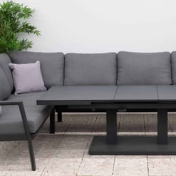 Modern outdoor sectional sofa with adjustable black dining table, weather-resistant cushions, and surrounding greenery for stylish garden or patio entertainment.