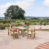Elegant outdoor patio with wooden dining table and benches, lush garden with blooming flowers, scenic countryside view, perfect for garden furniture and outdoor entertaining.