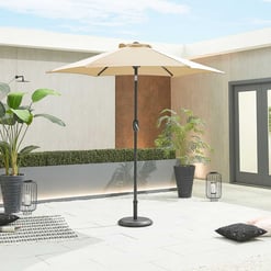 Elegant outdoor patio with a large beige umbrella, modern potted plants, and decorative accents, perfect for outdoor living and entertaining in a contemporary home setting.