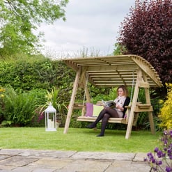 Relaxing outdoor garden swing with canopy, surrounded by lush colorful plants and flowers, perfect for outdoor living, relaxation, and enjoying nature.