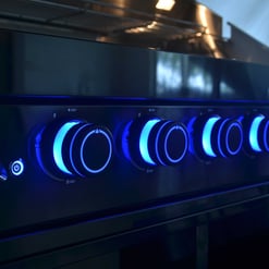 Blue illuminated stove burners with modern control knobs and digital display, showcasing high-quality kitchen appliances for home and garden upgrades.