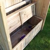 Natural wooden garden shed with planting trays and gardening tools for outdoor gardening and storage solutions.