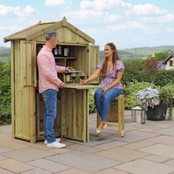 A compact wooden outdoor bar and garden shed with two people enjoying wine in a lush garden setting. Perfect for backyard entertaining, outdoor living, and garden storage solutions.