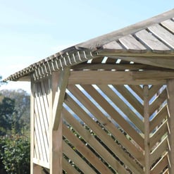 Rustic outdoor wooden gazebo with slanted roof and diagonal lattice walls, ideal for garden relaxation and outdoor entertaining. Perfect addition to any backyard landscape.