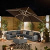 Stylish outdoor patio with modern wicker sectional sofa, large umbrella, ambient lantern lighting, lush potted plants, perfect for outdoor living and entertaining at Empire Home and Garden.