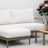 Elegant outdoor patio furniture with white cushions and a wooden coffee table, surrounded by lush flowering plants, perfect for garden relaxation and outdoor entertaining.