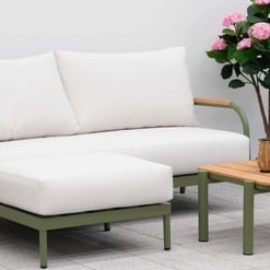 Elegant outdoor patio furniture with white cushions and a wooden coffee table, surrounded by lush flowering plants, perfect for garden relaxation and outdoor entertaining.