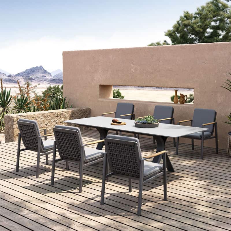 A photorealistic image of a modern grey aluminium garden dining set in a cozy UK garden during autumn. The scene is enhanced by autumn foliage, potted chrysanthemums, and a softly glowing fire pit, bathed in warm, late afternoon natural light.