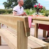 Handcrafted wooden outdoor dining bench and table set in a garden patio, perfect for outdoor entertaining and garden furniture enthusiasts.
