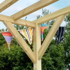 Colorful striped fabric bunting hanging on a wooden pergola for outdoor garden decor and party ambiance.