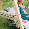 Relaxing outdoor garden swing with a woman enjoying a glass of white wine in a lush green backyard, showcasing beautiful garden furniture, perfect for backyard decor and outdoor leisure.