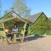 Stylish wooden outdoor gazebo with seating, perfect for garden lounging and entertaining. Beautiful backyard setting with lush greenery and cozy outdoor furniture.