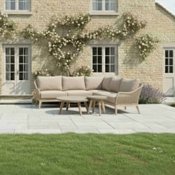 Bright outdoor patio furniture set with beige cushioned sectional sofa and wooden coffee tables, garden with blooming climbing roses, stone house exterior, perfect for garden decor and outdoor living in home and garden design.