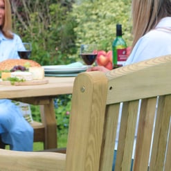 Sunny outdoor patio with natural wood garden furniture, perfect for alfresco dining and relaxation, surrounded by lush greenery. Ideal for outdoor entertaining and enjoying meals in garden settings.