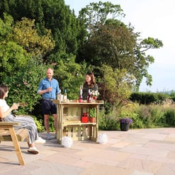 Relaxing outdoor patio with friends enjoying drinks amidst lush garden scenery, perfect for entertaining and outdoor gatherings.